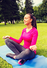 Image showing smiling woman meditating sitting on mat outdoors