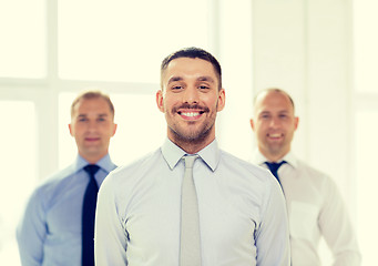 Image showing smiling businessman in office with team on back