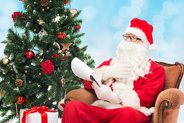 Image showing man in costume of santa claus with notepad