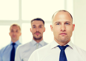 Image showing serious businessman in office with team on back