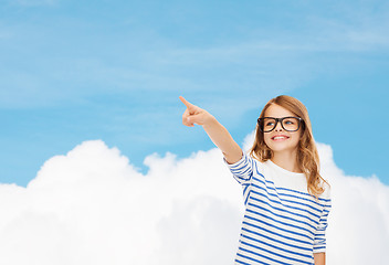 Image showing cute little girl in eyeglasses pointing in the air