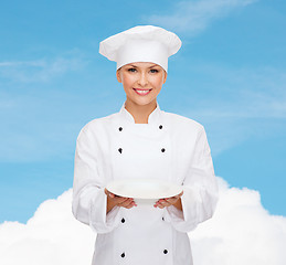 Image showing smiling female chef with empty plate