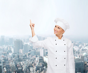 Image showing smiling female chef pointing finger to something