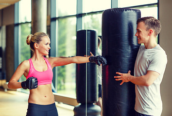 Image showing smiling woman with personal trainer boxing in gym