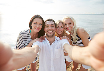 Image showing happy friends on beach and taking selfie