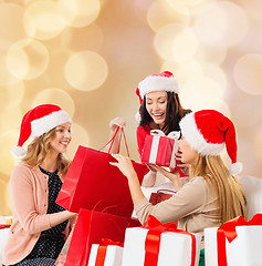 Image showing smiling young women in santa hats with gifts