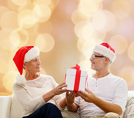 Image showing happy senior couple in santa hats with gift box