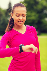 Image showing smiling young woman with heart rate watch