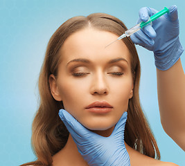 Image showing beautiful woman face and hands with syringe