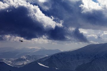 Image showing Helicopter in winter mountains and cloudy sky