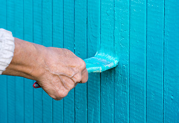 Image showing Hand with a paint brush paints wooden wall