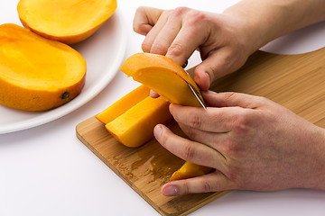 Image showing Two Male Hands Peeling A Juicy Mango Fruit Chip