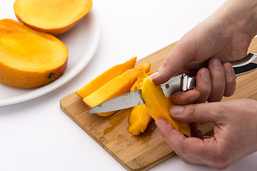 Image showing Close-up Of Two Hands Peeling Juicy Mango Pieces