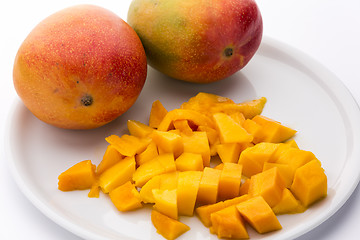 Image showing Juicy Mango Dice And Two Entire Mangos On A Plate