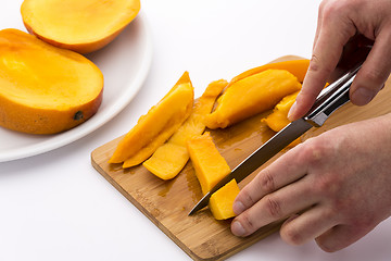 Image showing Two Hands Dicing A Mango Wedge With A First Cut