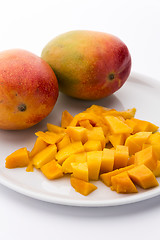 Image showing Mango Cubes And Two Whole Mangos On A White Plate