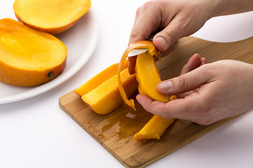 Image showing Hands Separating Mango Fruit Flesh From Its Skin