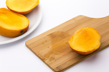 Image showing Third Of A Mango And Its Juice On Wooden Board