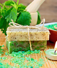 Image showing Soap homemade and candle with nettles in mortar on board