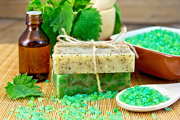 Image showing Soap homemade and oil with nettles in mortar on board