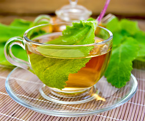 Image showing Tea with sage in cup on bamboo napkin