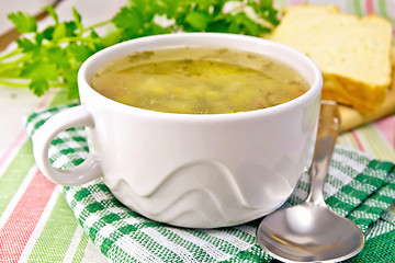 Image showing Soup of green peas with bread on tablecloth