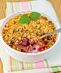 Image showing Crumble cherry in bowl with spoon on napkin