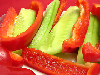 Image showing Slitted red pepper and cucumber on a white plate and placemat