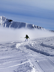 Image showing Snowboarder downhill on off-piste slope in sunny day