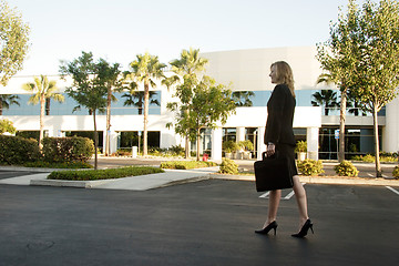 Image showing Business woman walking through parking lot carrying briefcase