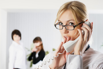 Image showing Attractive woman calls by wire phone in office