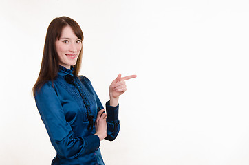 Image showing Young girl in a blue blouse pointing at empty space on left