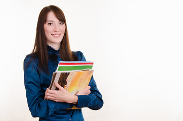 Image showing Young girl holding a stack of magazines