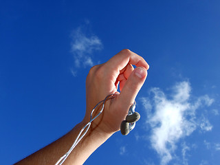 Image showing Hand with small headphones on a background of the blue sky