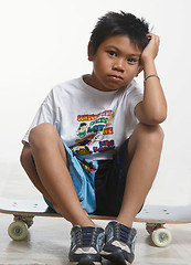 Image showing Sad boy sitting on his skateboard