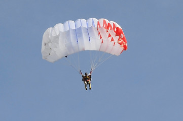 Image showing The parachutist goes down on a multi-colored parachute.