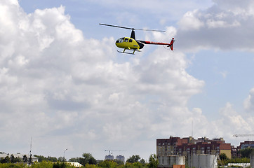 Image showing The small yellow helicopter in the sky.