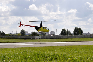 Image showing The small yellow helicopter in the sky.