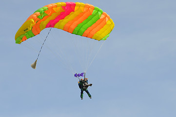 Image showing the parachutist goes down on a multi-colored parachute.