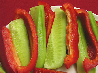 Image showing Slitted red pepper and cucumber on a white plate and placemat