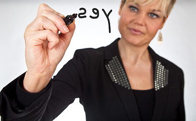 Image showing Studio portrait of a cute blond girl writing on a transparent wa