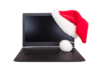 Image showing Modern open laptop with red santa claus hat put on lcd corner