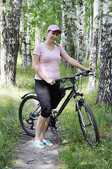 Image showing The woman with bicycle in the birch wood.