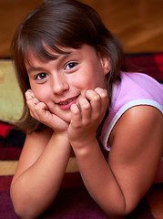 Image showing smiling girl lying on the floor resting his head in hands