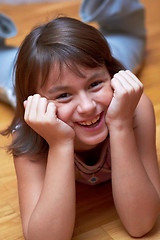 Image showing smiling girl lying on the floor resting his head in hands