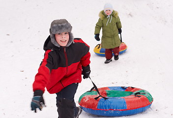 Image showing boy and girl having fun pull snow tube up