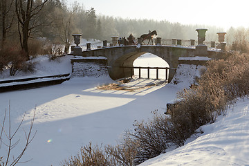 Image showing winter sunny landscape with horse-drawn carriage on old bridge 