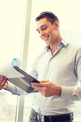 Image showing smiling businessman with clipboard in office