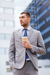 Image showing young serious businessman with paper cup outdoors