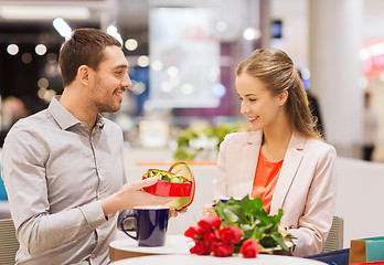 Image showing happy couple with present and flowers in mall